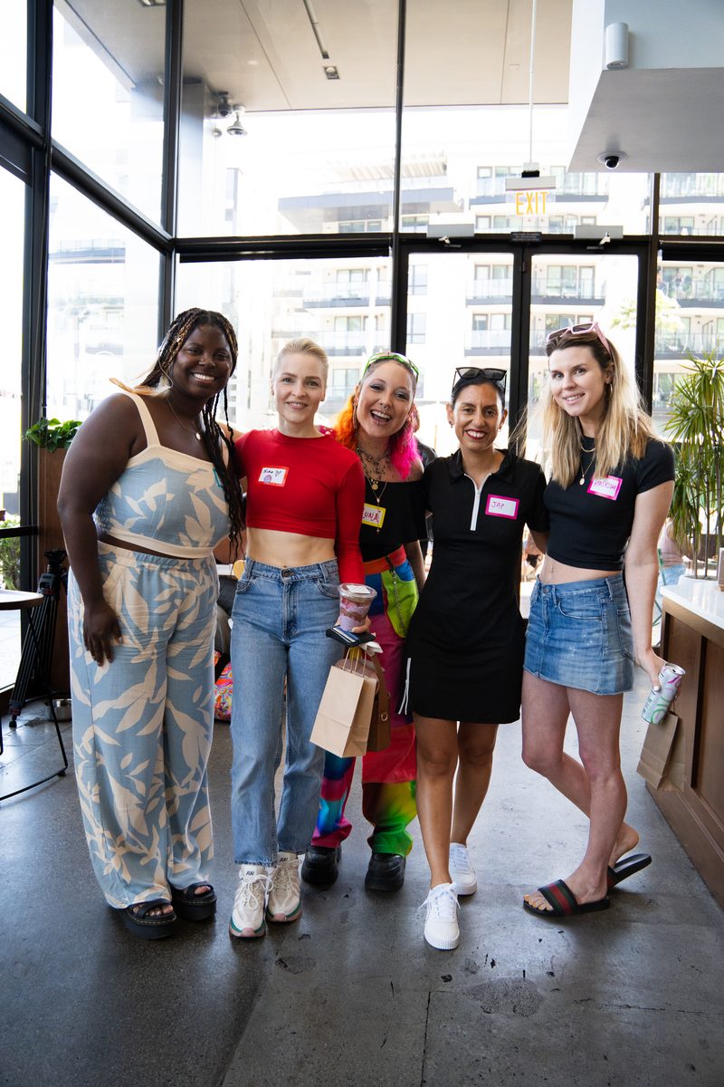 five friends standing together, smiling, name tags on